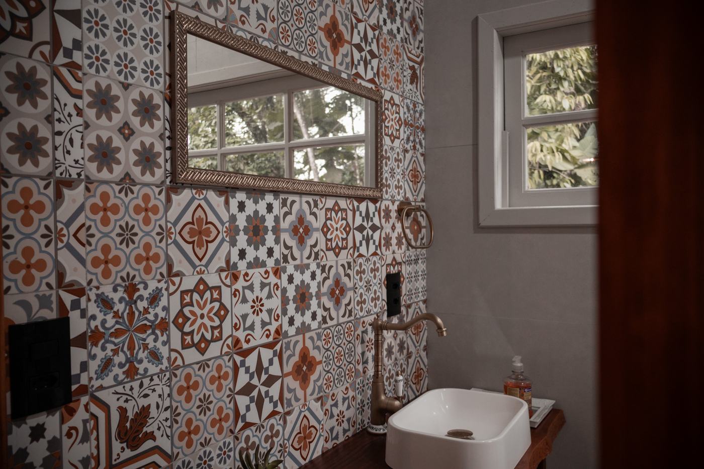 Banheiro com azulejos artesanais e janela para a mata na Tiny House Herrmann Haus